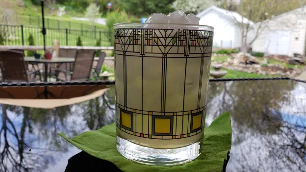 A stained-glass patterned tumbler of citrus water on a patio table