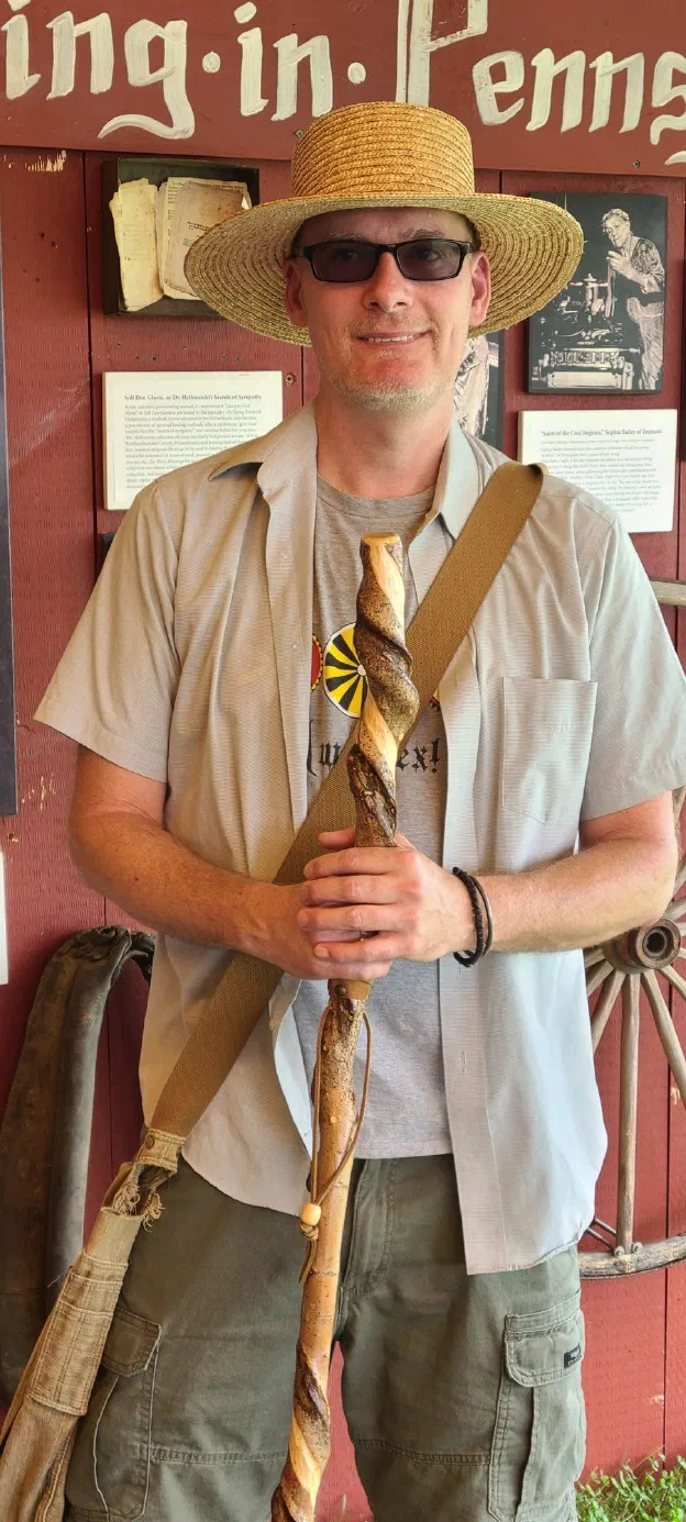 Robert Phoenix at a Pennsylvania German folklife exhibit, holding a hand-carved throw-stick