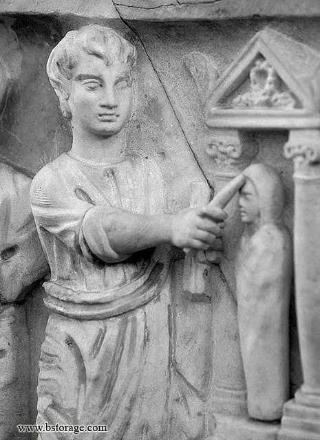 A Roman relief of a robed figure touching a smaller wrapped body with a rod