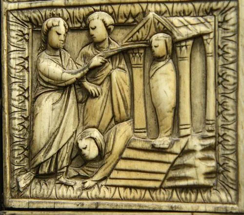 A carved ivory panel of Christ raising Lazarus, touching the shrouded body with a wand