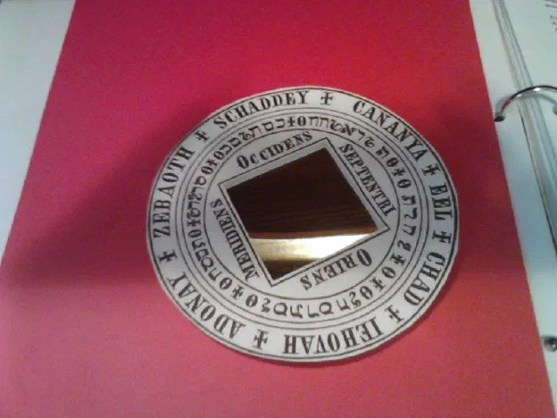 A black scrying mirror set in a brass disc engraved with divine names and crosses