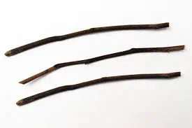 Three slender peeled twigs laid side by side on a white ground